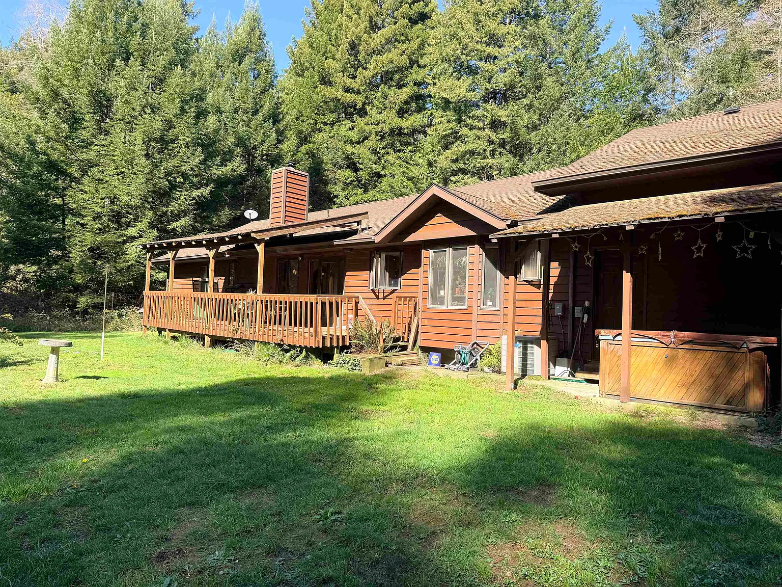 Back of the house showing the full-length covered deck and the redwood-lined backyard.