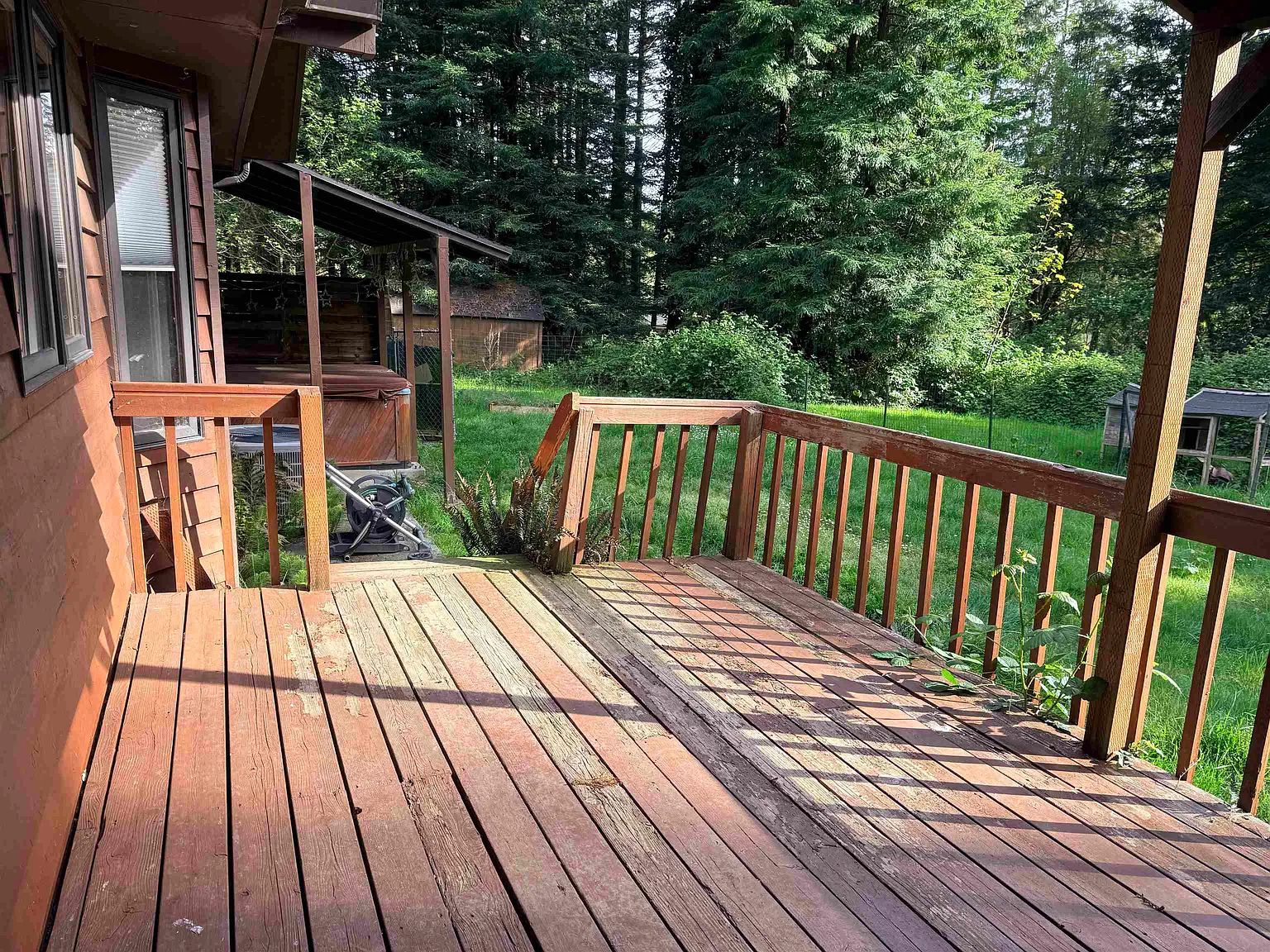 Lower deck with hot tub under a covered wooden structure.