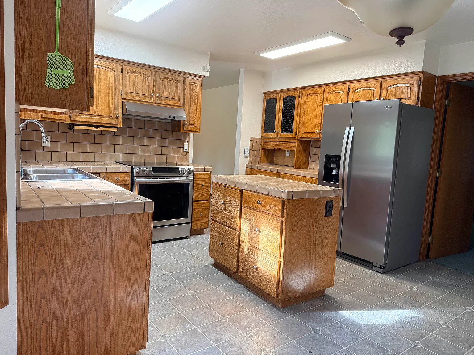 Kitchen from the other angle, with a wood island, stainless fridge, and oven.