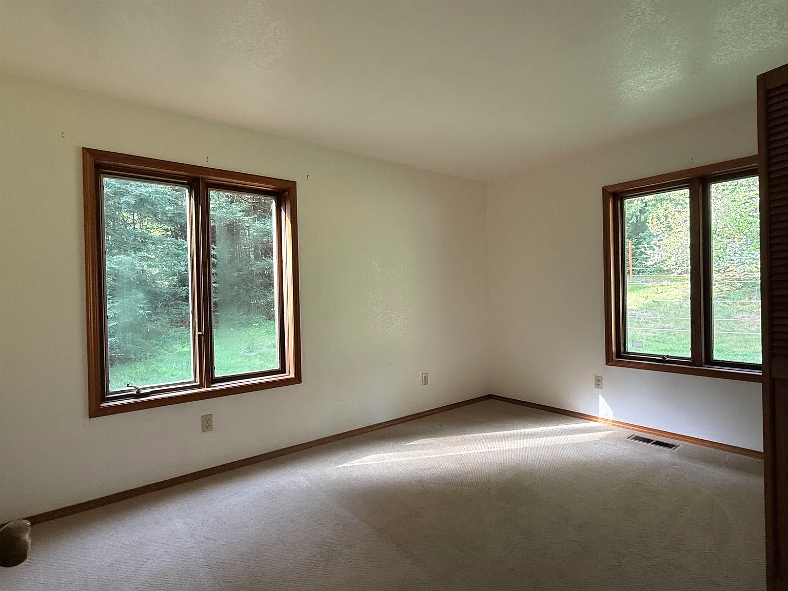 A bright bedroom with windows on two walls.